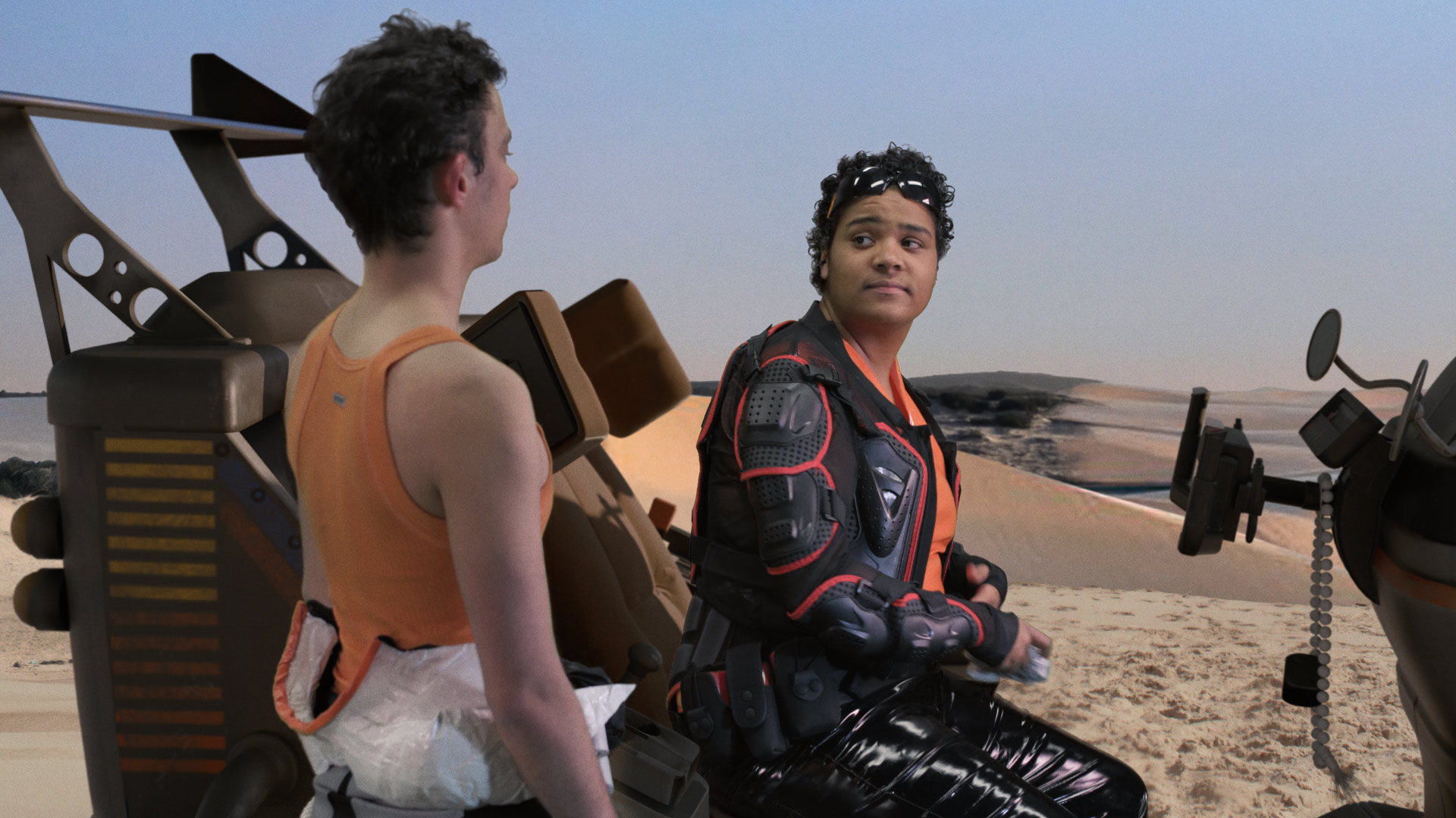 Film still of Mishaps in Spacetime: Cosmo and Jesse have an interaction, while Jesse prepares her jetski against a landscape of dunes.
